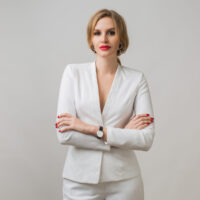 portrait of young attractive lady in white suit, sexy and confident, independed business woman, elegant style, red lips, serious expression of face, looking in camera, crossed arms, smile